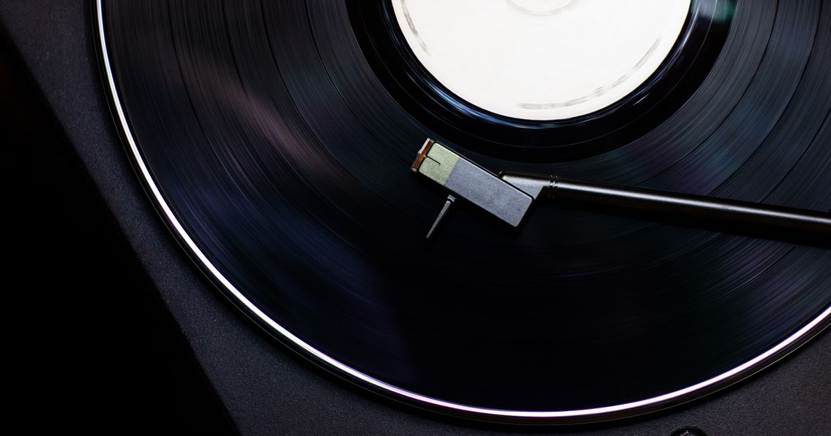 Close-up of a turntable cartridge and stylus resting on the grooves of a black vinyl record
