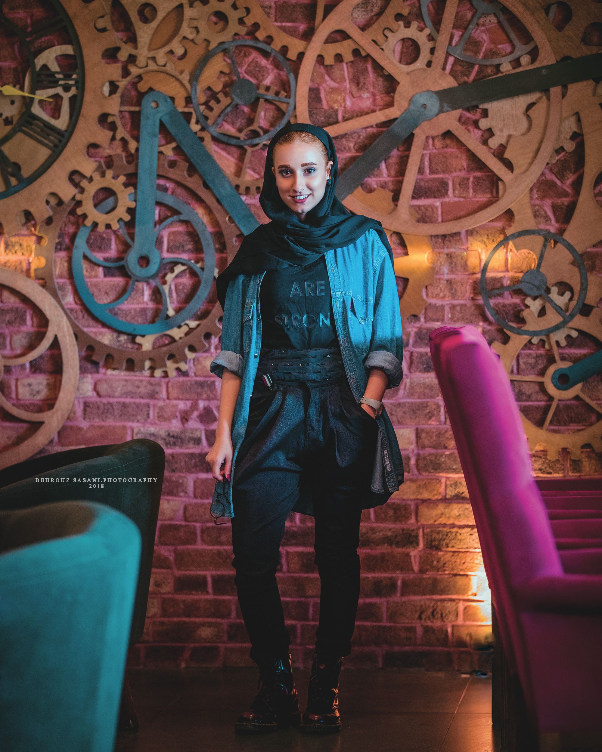 Stylish woman posing in a modern Tehran cafe with artistic decor.