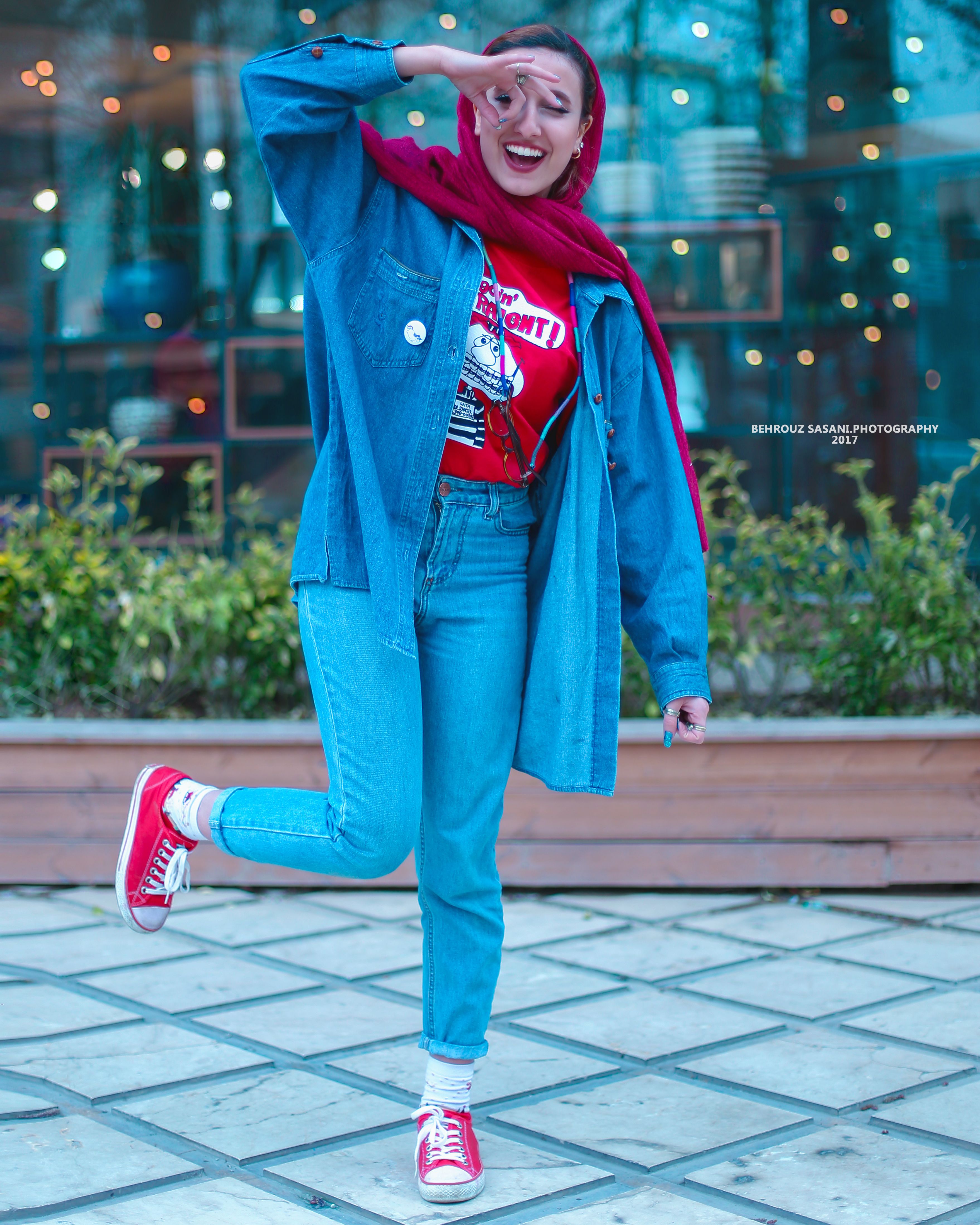 Smiling woman in denim and red headscarf posing outdoors in Tehran.