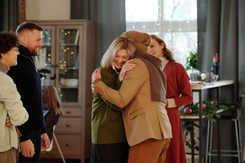 Free Family members embracing warmly at a festive indoor gathering, spreading holiday cheer. Stock Photo