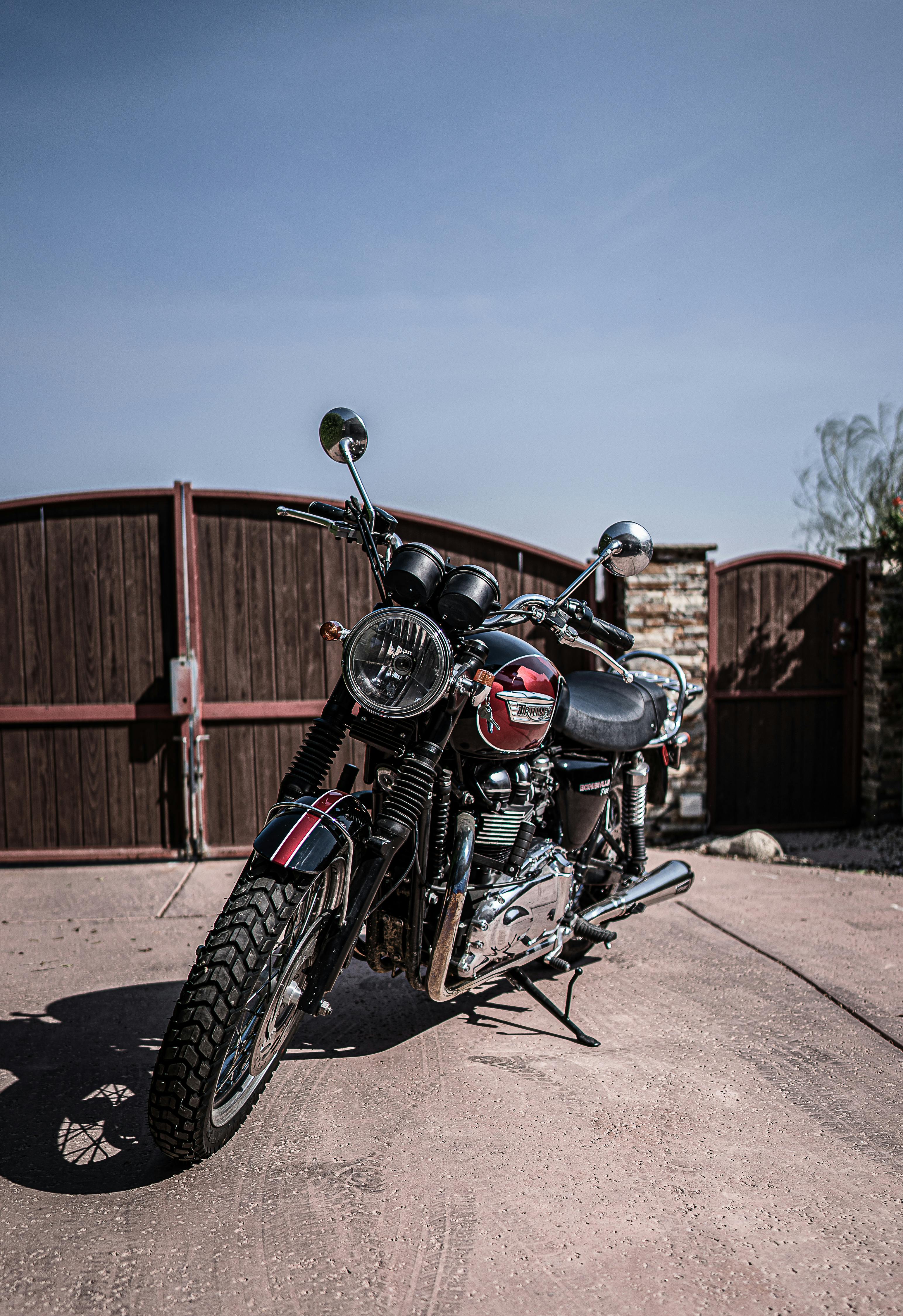 Shiny vintage motorcycle parked in yard on sunny day · Free Stock Photo