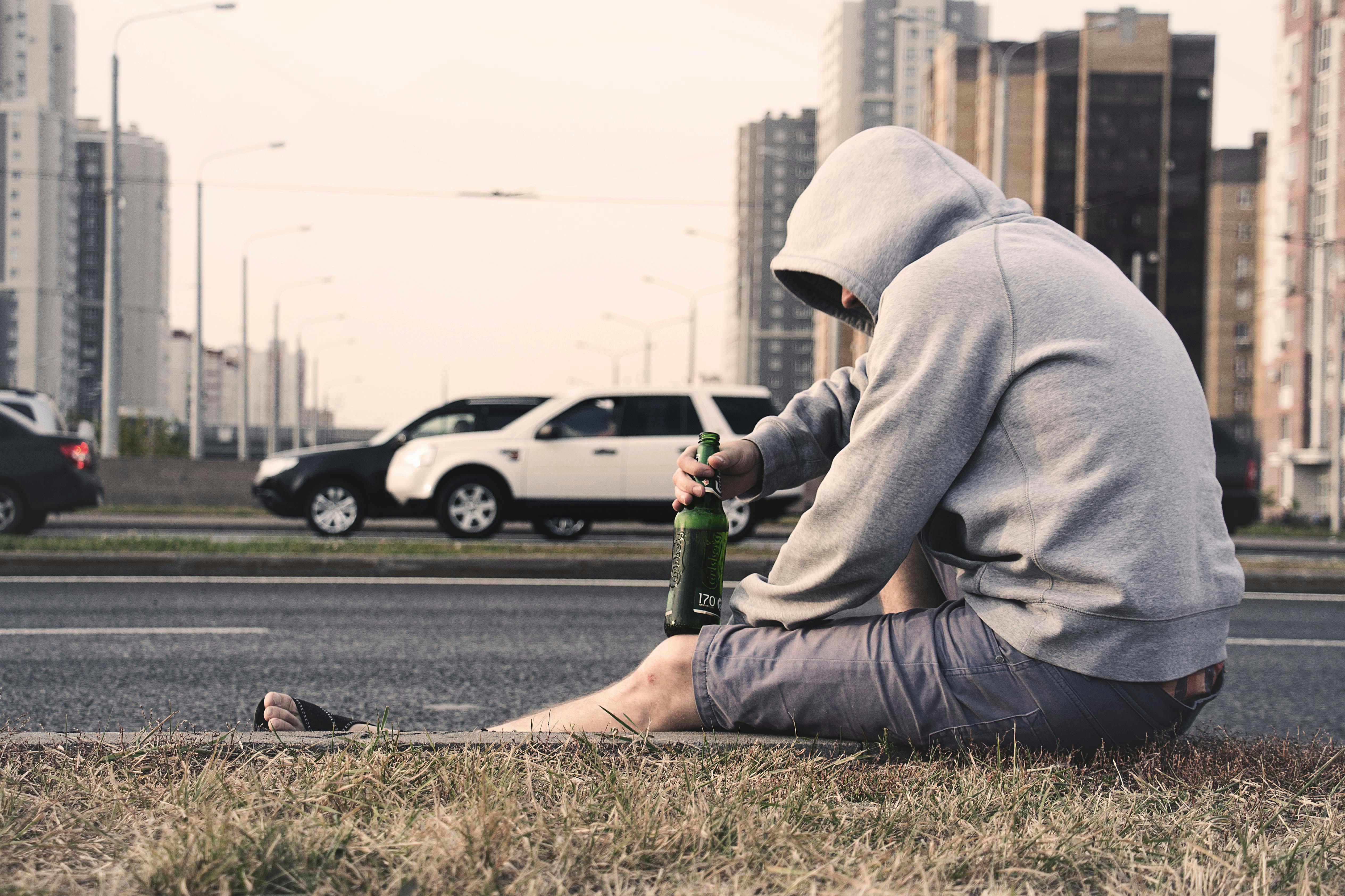 person in gray hoodie holding beer