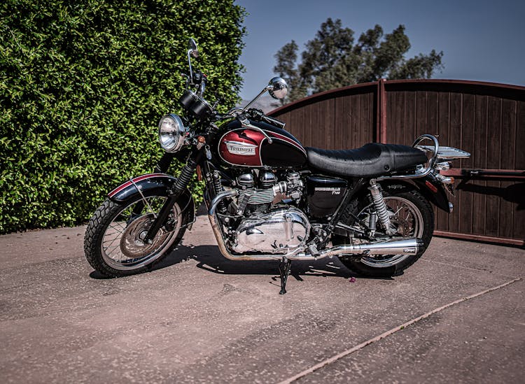 Shiny Vintage Motorcycle Parked In Yard On Sunny Day