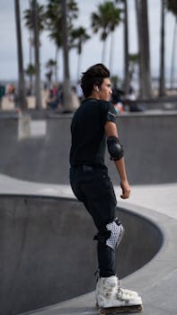 Teenager skating in Venice Beach park wearing protective gear, showcasing youth and freedom.