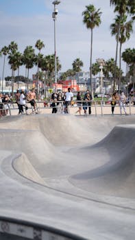 A lively scene at a skate park with people enjoying the sunny outdoors surrounded by palm trees.