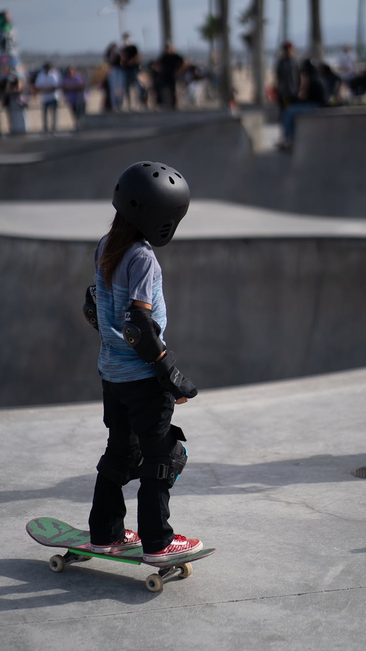 Anonymous Kid Wearing Protection Equipment While Riding Skateboard