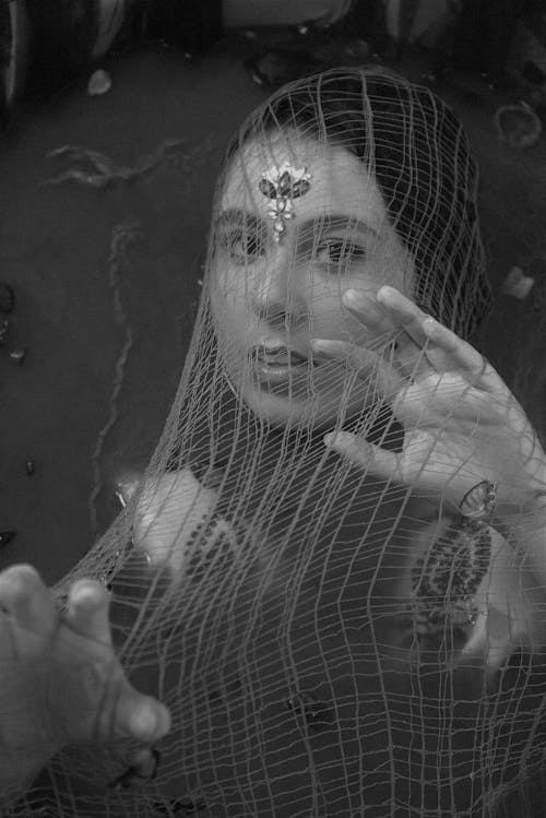 
A Grayscale of a Woman Covered with a Net