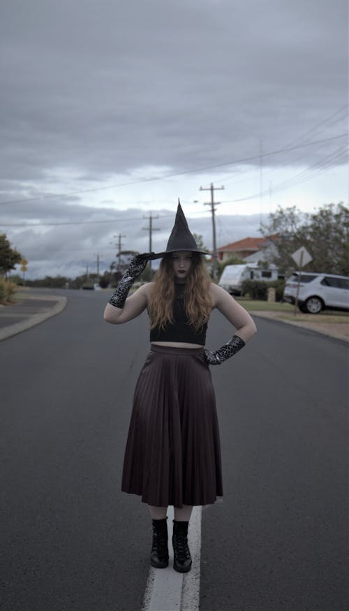 Woman Wearing Black Witch Hat Standing on the Road