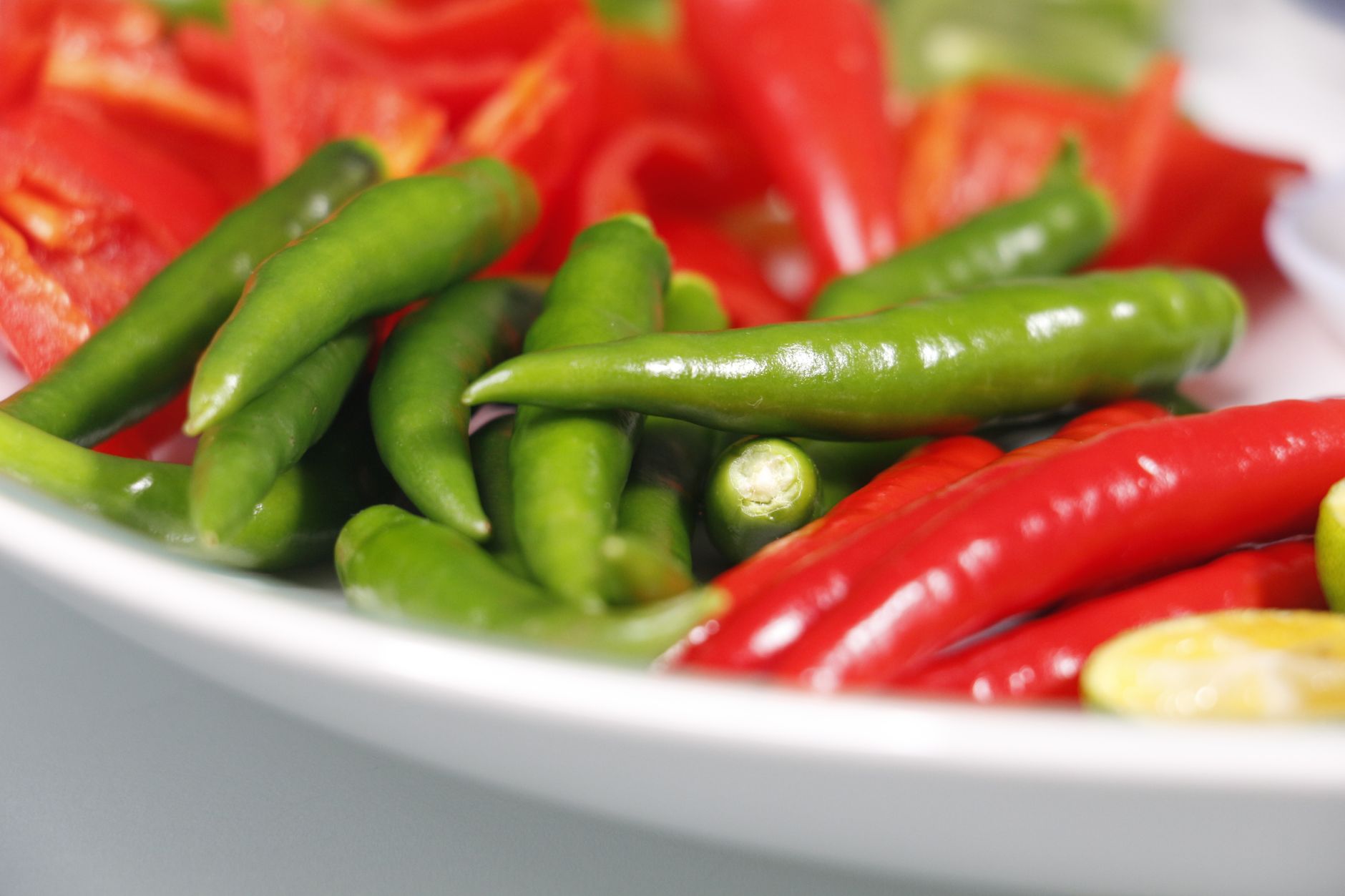 Vibrant close-up of fresh red and green chili peppers on a plate, ideal for food concepts.