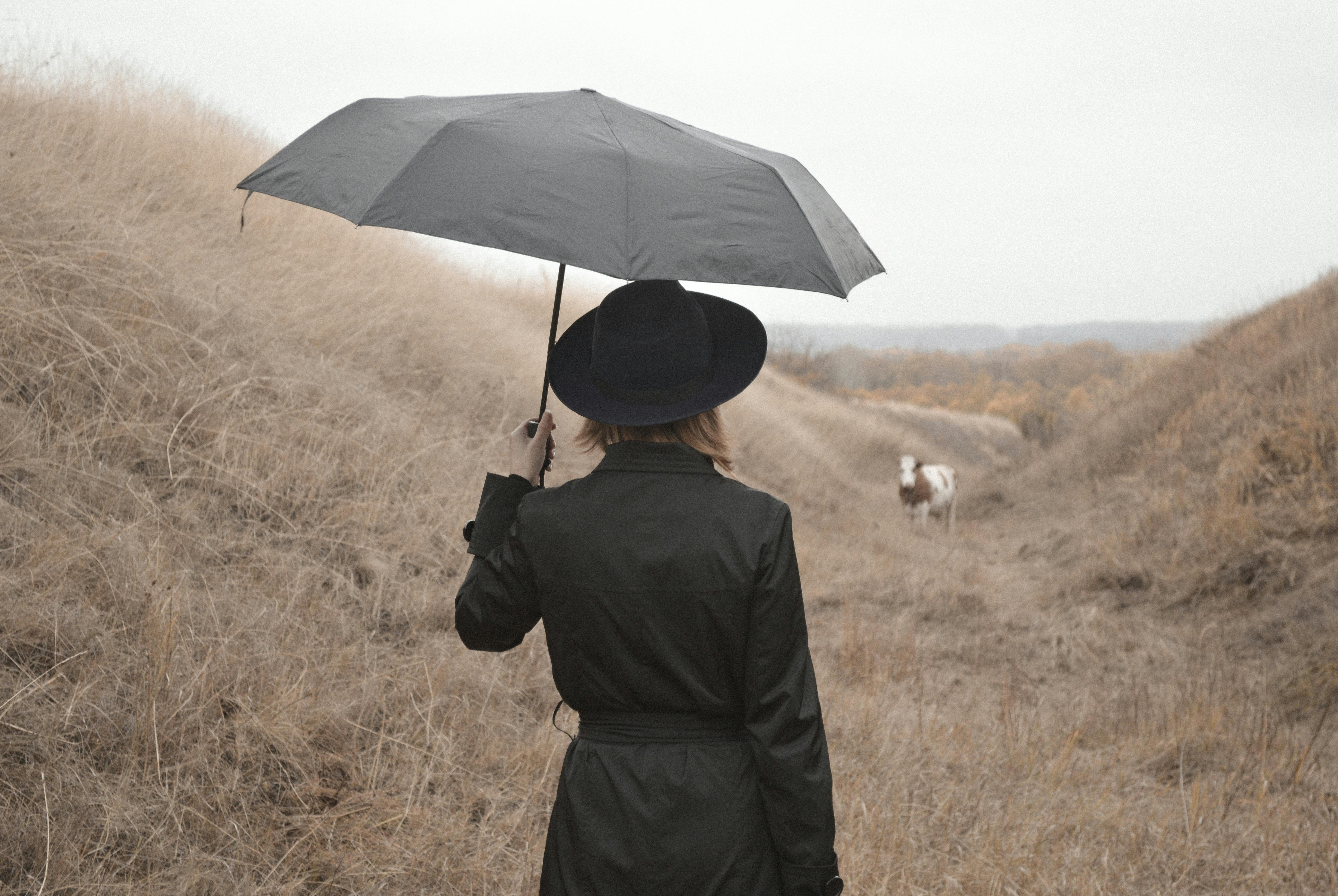 woman with umbrella standing in countryside