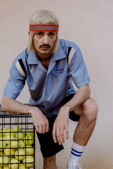 Man in retro tennis outfit with headband and tennis ball basket.