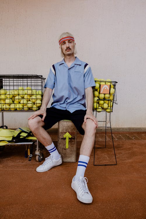 Photograph of a Man with a Sweatband Sitting Near Tennis Balls