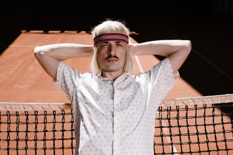 Photograph Of A Man Leaning On A Net While His Hands Are Behind His Head