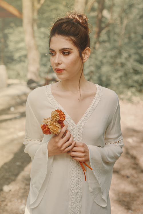 Portrait of a Woman in a White Dress Holding Flowers
