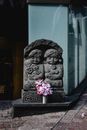 Flowers in a Tin Vase in Front of a Stone Sculpture