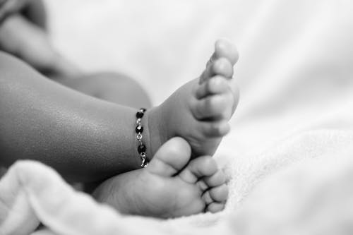 Grayscale Photo of Baby's Feet With Anklet