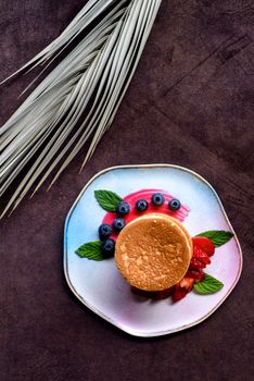 Colorful pancake breakfast with fresh berries and mint on artistic plate, top view.