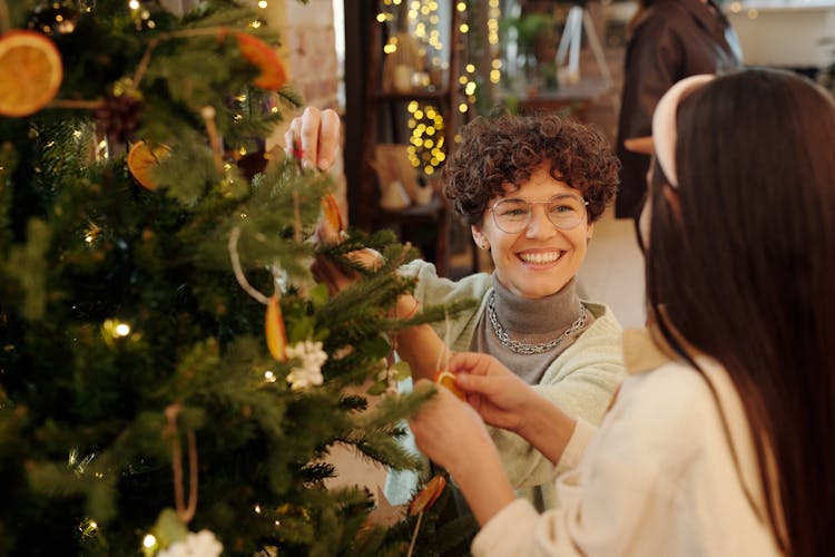 Mother And Daughter Decorating A Christmas Tree