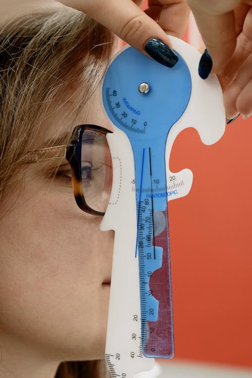 Crop ophthalmologist measuring eyewear lens on woman