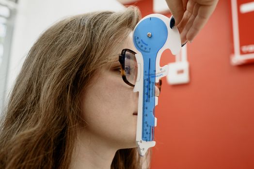 验光师用蓝色测量工具为一位年轻女性患者评估视力