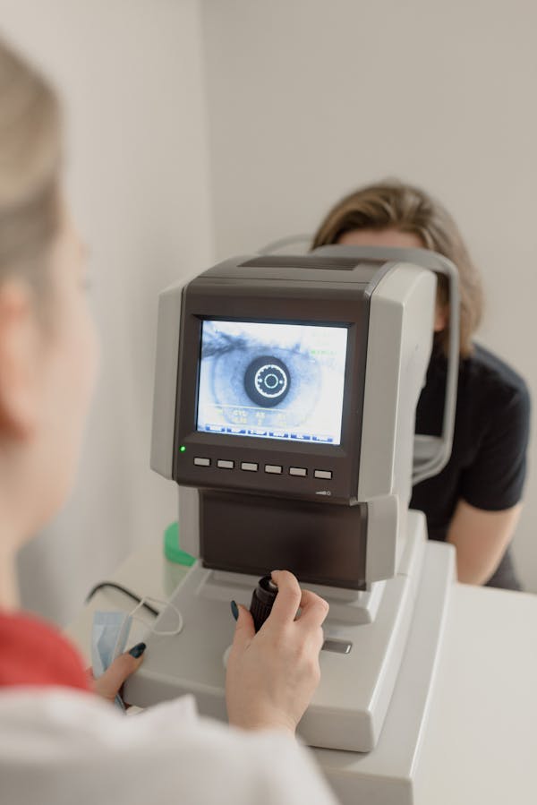 Unrecognizable ophthalmologist checking eyesight of woman on vision screener