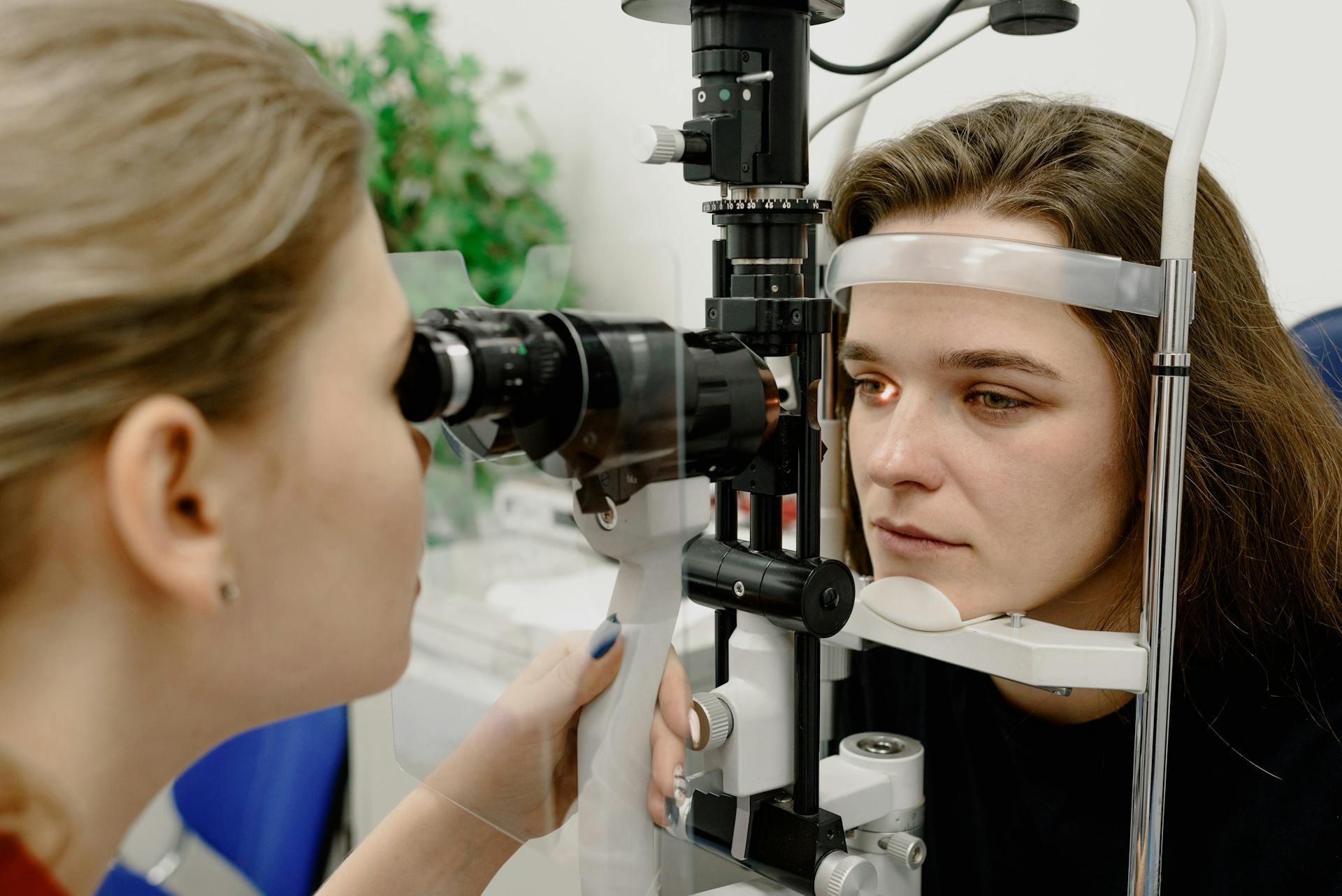 Concentrated female medical specialist using professional tool for checking vision of patient in contemporary ophthalmology clinic