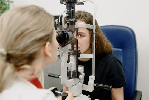 Free Female doctor using modern medical device for female patient while checking eyesight in clinic during check up Stock Photo