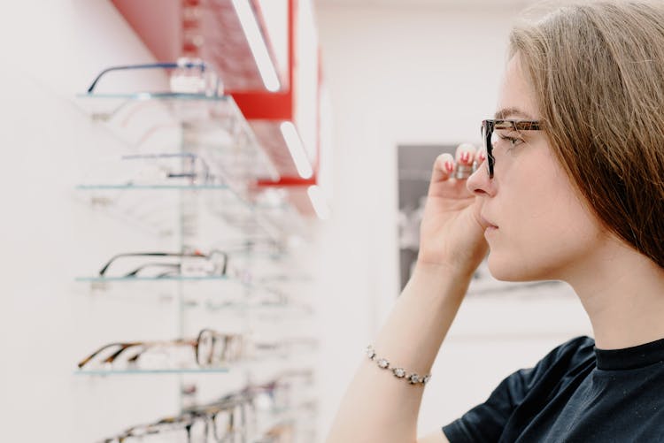 Young Woman Adjusting Glasses In Optical Store