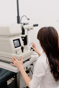 女验光师在诊所使用数字眼科检查设备
