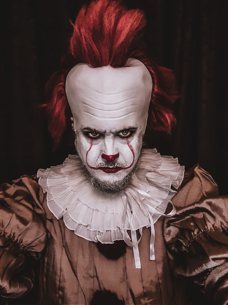 A Person Costumed As Pennywise Seriously Looking At The Camera