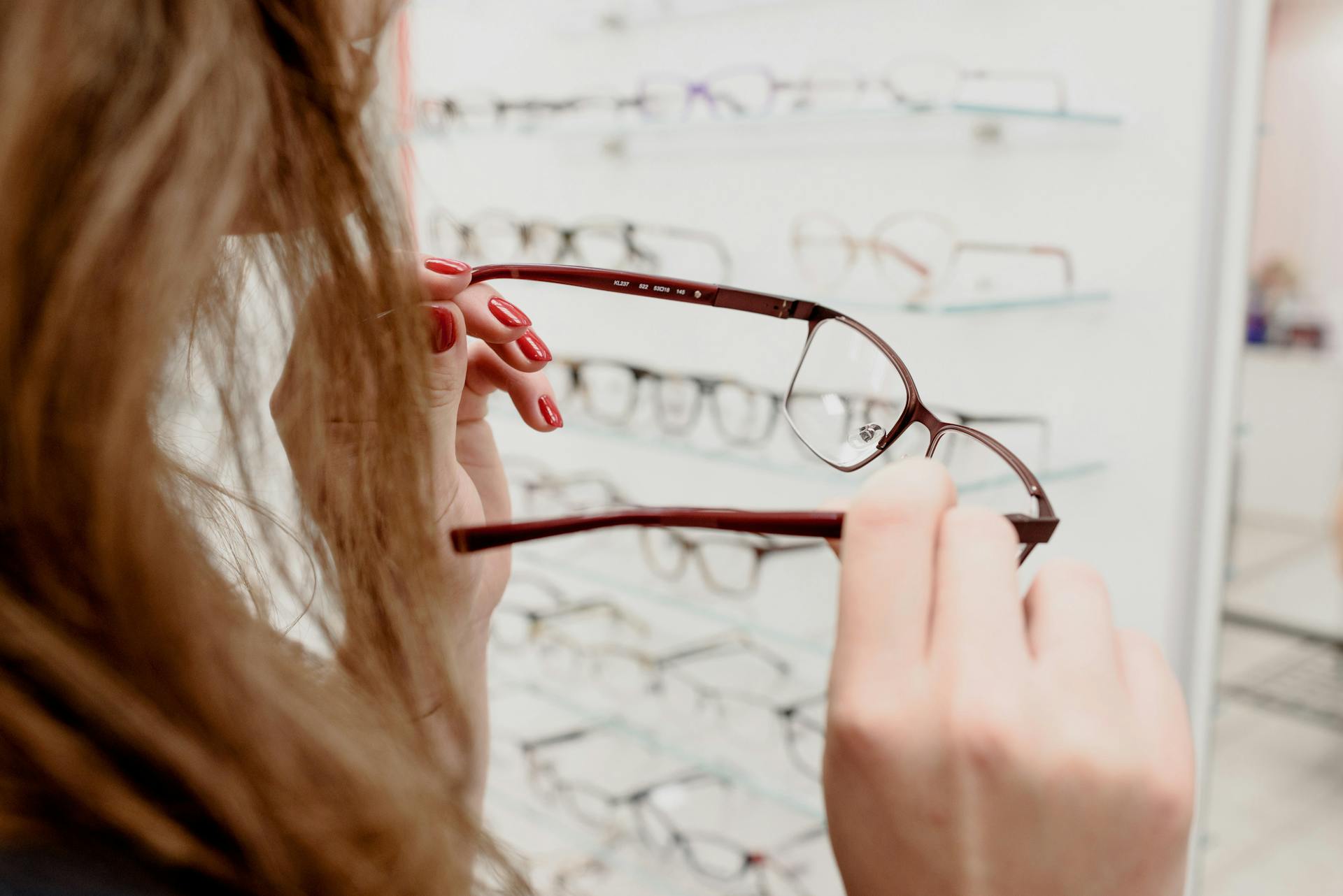 A woman examines a pair of eyeglasses in an optical store, deciding on the perfect fit.