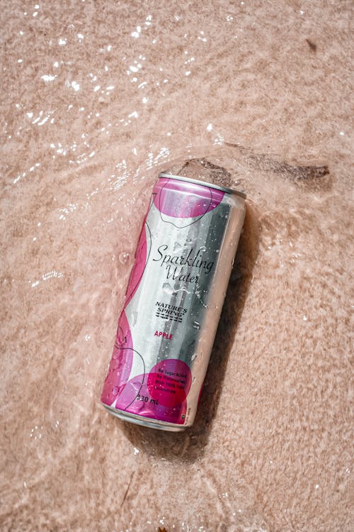 Free Pink and Silver Bottle on Brown Textile Stock Photo