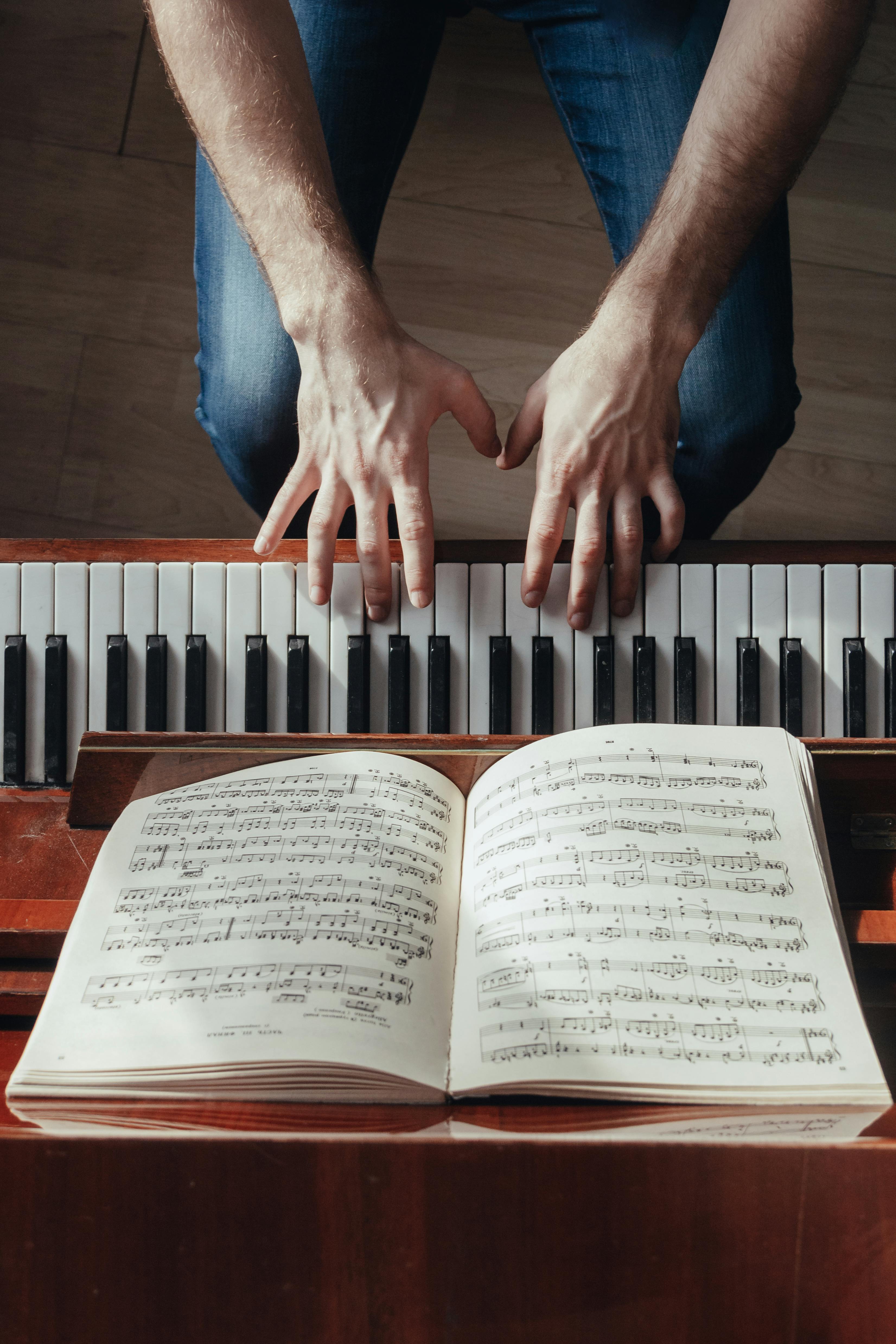 crop pianist playing piano with sheet music on stand