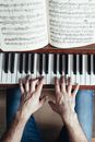 Faceless musician playing piano using music paper