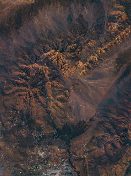 Amazing aerial view of sandy volcanic terrain with rocky mountains on sunny day