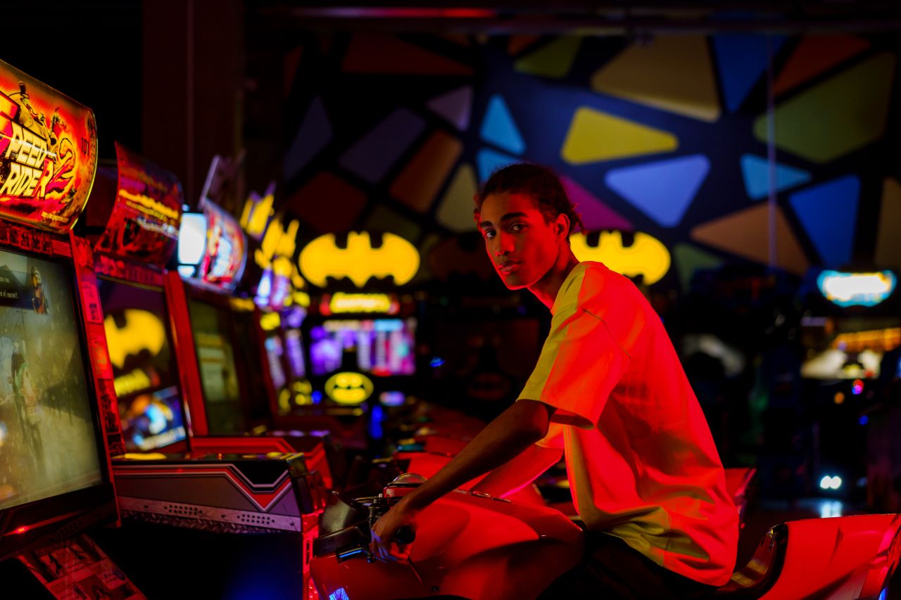 a young adult plays an arcade game in a vibrant illuminated gaming cen