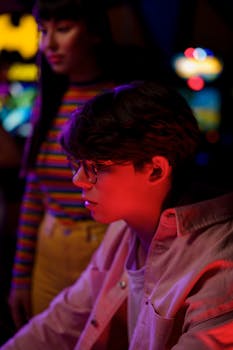 两名年轻人沉浸在灯光缤纷、氛围热烈的街机游戏中