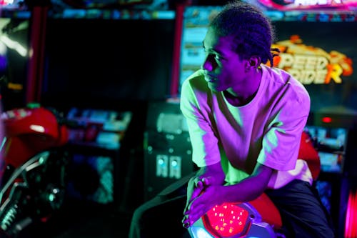 Man Riding a Motorcycle Arcade Game Machine while Looking Afar