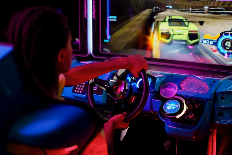 Player at a neon arcade racing cabinet — cottonbro studio on Pexels
