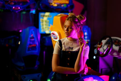 Woman Sitting Inside an Arcade Game Amusement Park while Looking Afar