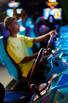 Young adult playing a racing game at an indoor arcade with vivid lighting.