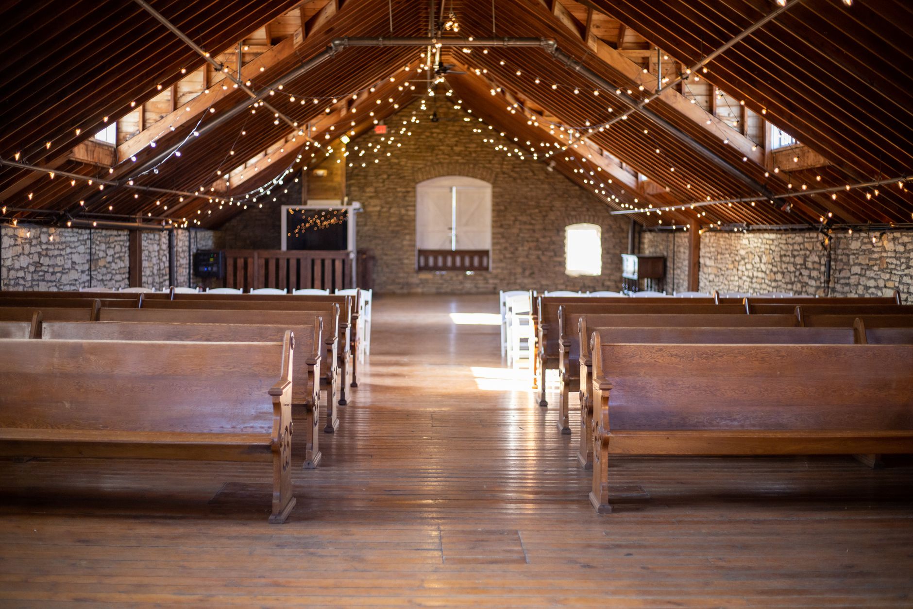 Rustic church interior featuring wooden pews and fairy lights. Warm and inviting atmosphere in Rochester, MN.