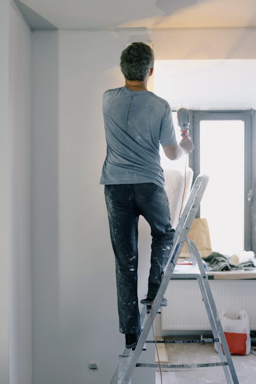 Free Male builder with instrument in apartment Stock Photo