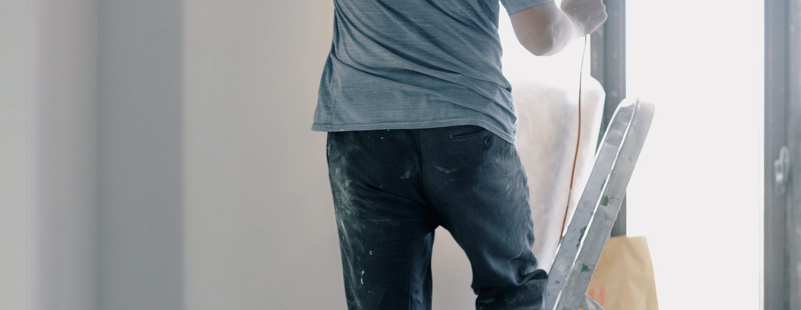 Handyman on a ladder doing renovation work indoors