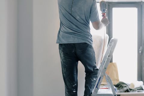 Handyman on a ladder doing renovation work indoors