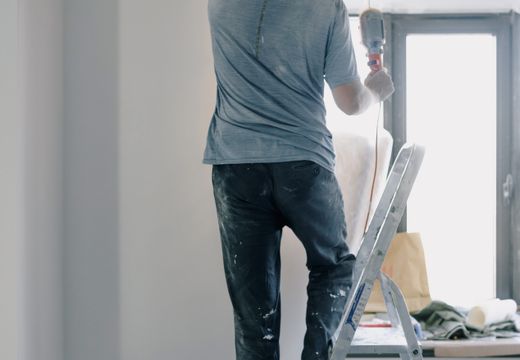 Handyman on a ladder doing renovation work indoors