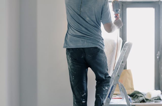 Handyman on a ladder doing renovation work indoors