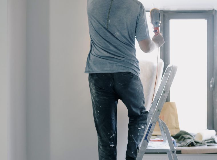 Handyman on a ladder doing renovation work indoors