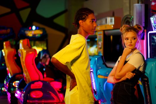 A young couple stands inside an arcade, enjoying the vibrant atmosphere and colorful games.