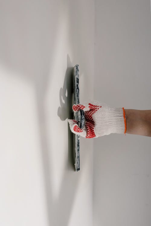 Free Crop anonymous painter in gloves preparing wall for painting works during renovation process in apartment Stock Photo